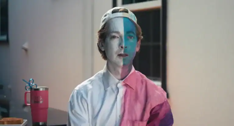 man wearing a backwards baseball cap with blue and white face paint on.