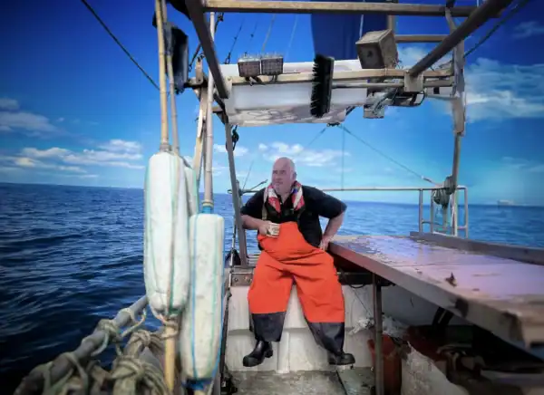 Man sitting on a boat looking out at the sea.