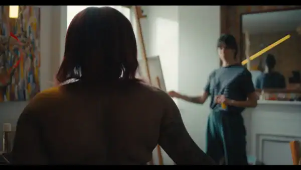 A woman paints another woman who is naked.