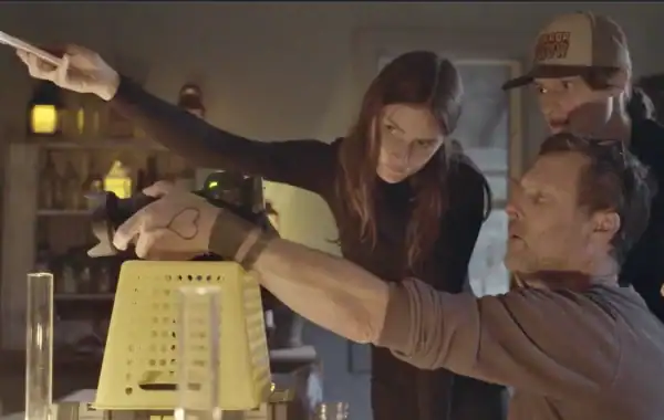 Two people working together in a film set, one holding a camera and the other adjusting lighting.