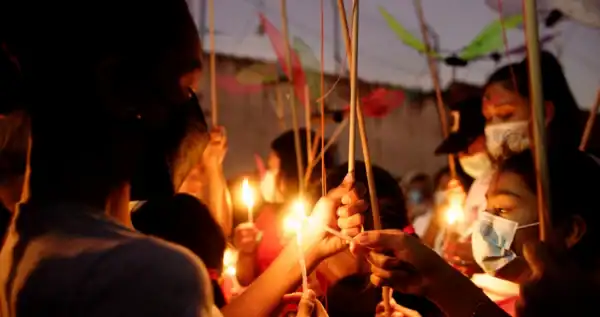 A group of people holding candles and lighting them for eachother.