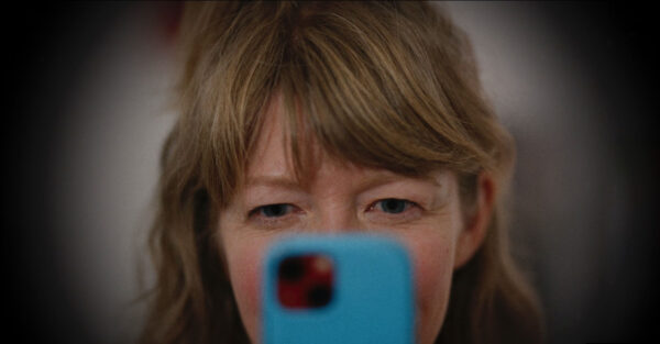 A woman focuses intently on a smartphone, displaying a thoughtful expression, suggesting concentration.