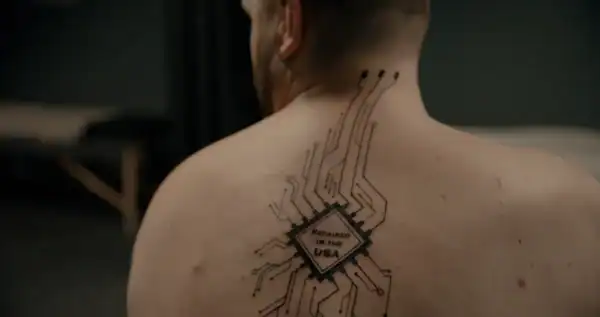 Close-up of a person's back with a tattoo of a circuit board design and the text 'Resisted for the USA' in the center.
