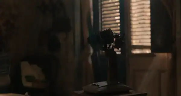 Vintage film projector in a dimly lit room with wooden blinds.