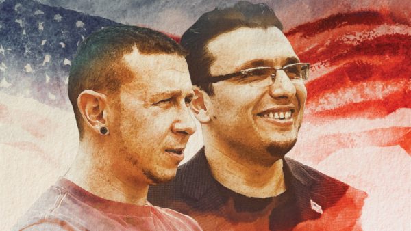Two men stand in front of a stylized American flag background, one wearing glasses and smiling, the other looking ahead with a neutral expression.