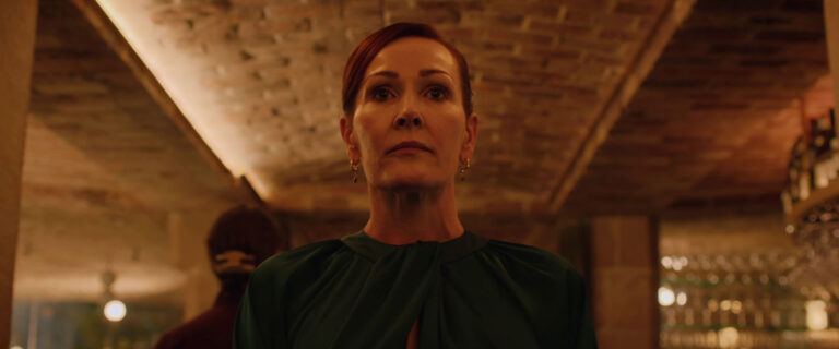 A woman stands in a warmly lit, brick-walled space, looking determined.