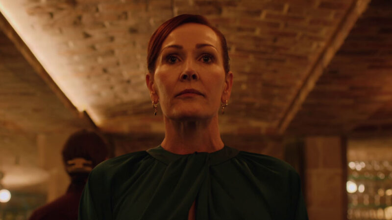 A woman stands in a warmly lit, brick-walled space, looking determined.