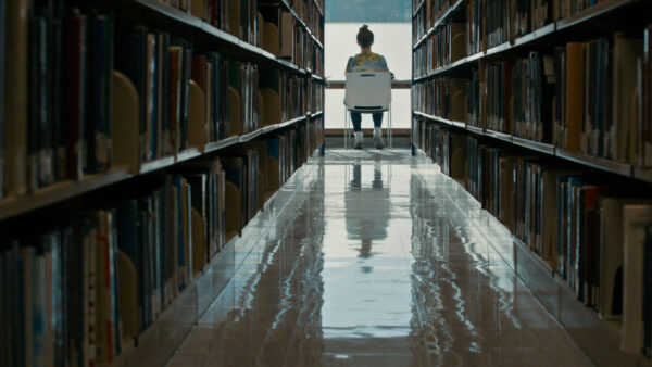 A long library hallway with a person sitting in the middle.