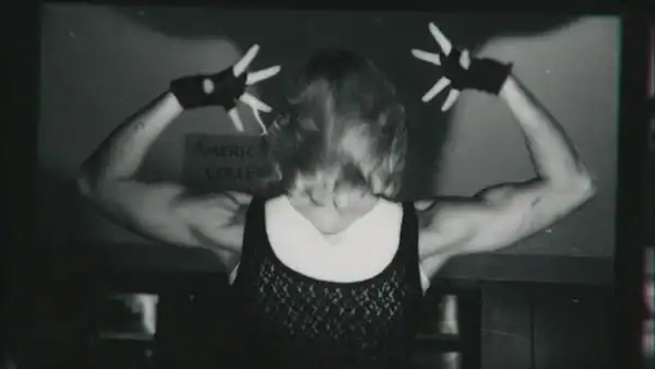A woman wearing a black and white tank top flexes her back.