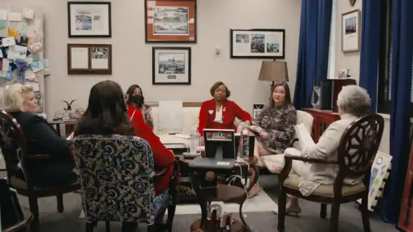 A group of older women sit in a office lounge area discussion with each other.