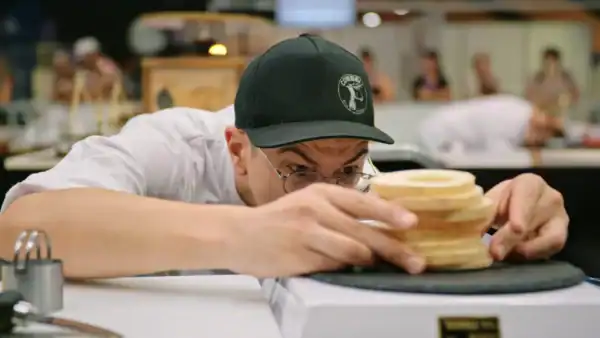 A man precisely weighs a block of cheese.