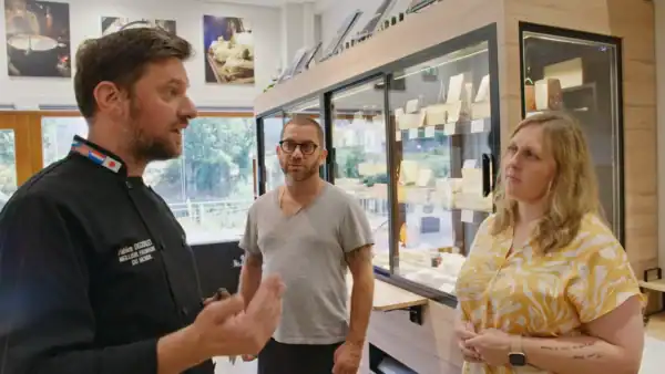 Three people discuss in an indoor setting.