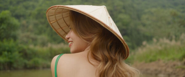 A woman, smiling, looking over her shoulder to the left.